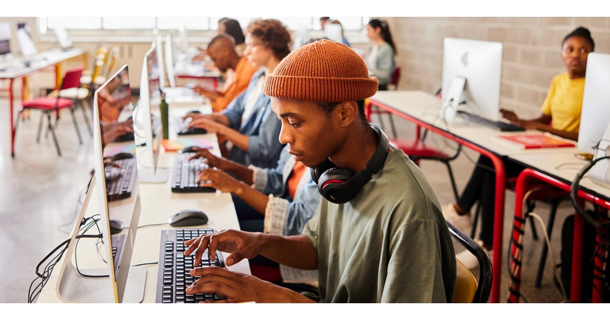 where to learn digital skills; a young man on a pc with people in the background
